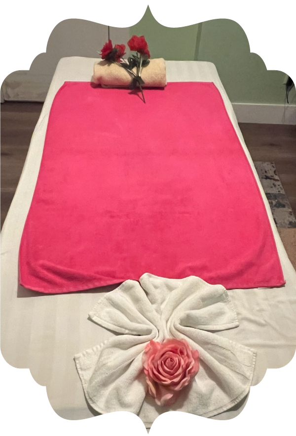 Beautifully arranged massage bed with pink towels and rose towel art, showcasing the caring and healing touch offered at Golden Hands Massage in Fresno.