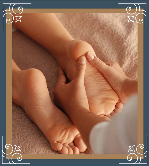 Professional therapist applying pressure to sore feet during a reflexology foot massage session to relieve leg cramps and improve blood circulation.