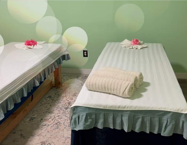 Dual massage table setup with fresh linens in a private room, perfect for couples or friends seeking shared relaxation at Golden Hands Massage.